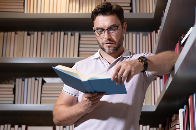 Insegnante o professore di mezza età nella biblioteca della scuola che legge il libro insegnanti di giorno insegnante in classe kn