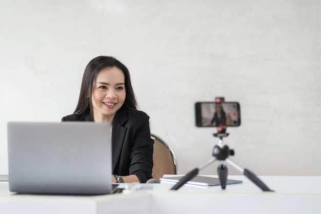 Insegnante universitario femminile asiatico adulto che insegna online tramite videoconferenza agli studenti a casa