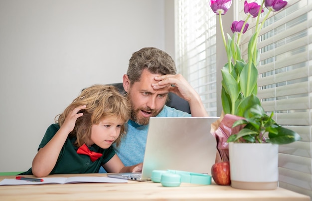 Insegnante uomo maturo o papà che aiuta il figlio bambino con i compiti scolastici in videoconferenza al computer