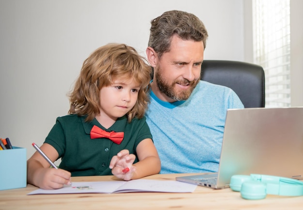 Insegnante uomo maturo o papà che aiuta il figlio del bambino con i compiti a scuola sul blog di famiglia del computer