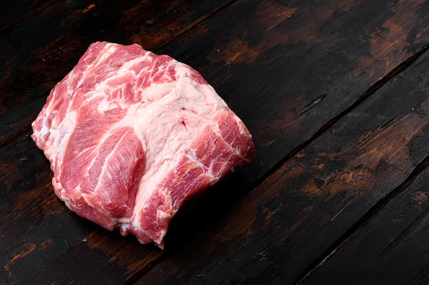 Insieme crudo del collo della carne di maiale, sul vecchio fondo di legno scuro della tavola, con lo spazio della copia per testo