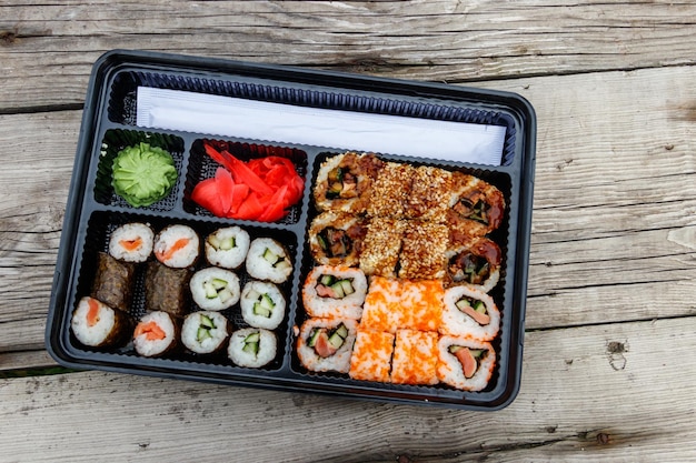 Insieme dei rotoli di sushi in scatola di plastica sulla tavola di legno