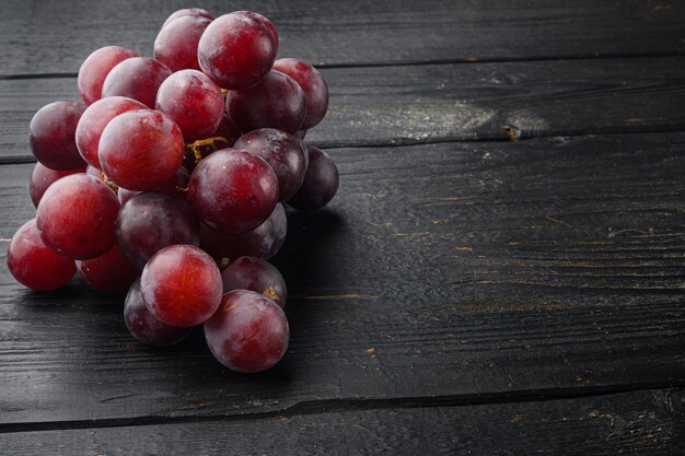 Insieme dell'uva matura, frutti rosso scuro, sulla tavola di legno nera