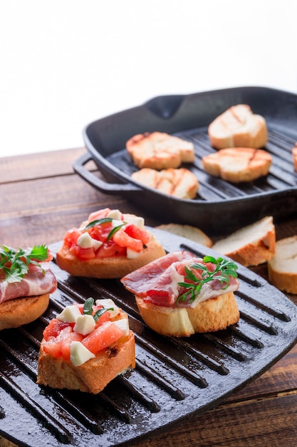 Insieme della Bruschetta sulla leccarda nera su di legno. Gustoso antipasto