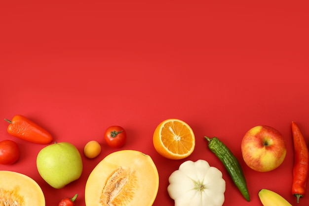 Insieme di diverse verdure e frutta su sfondo rosso