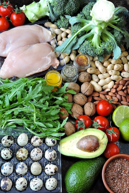 insieme di prodotti della dieta cheto a basso contenuto di carboidrati. Verdure verdi, noci, filetto di pollo, semi di lino, uova di quaglia, pomodorini.