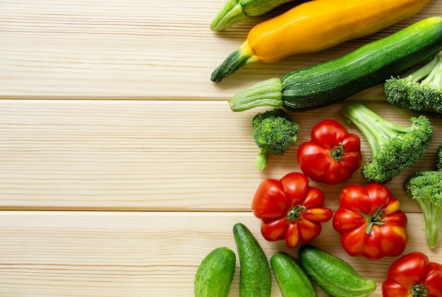 Insieme di varie verdure su uno sfondo in legno chiaro. Spazio per il testo.