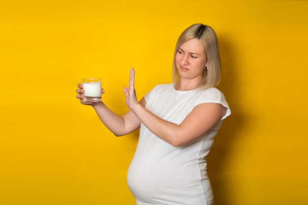 Insoddisfatta donna incinta, bionda rifiuta di prendere le pillole un bicchiere di latte. dieta durante la gravidanza