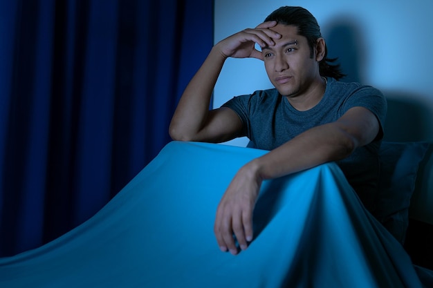 Insonnia Uomo depresso seduto a letto la notte non riesce a dormire a causa dell'insonnia