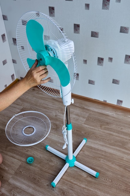 Installazione del ventilatore da pavimento a casa la donna monta l'elettrodomestico con le proprie mani