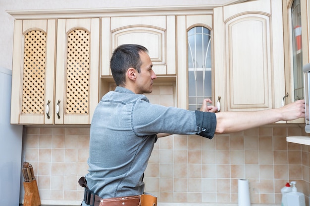 Installazione della cucina. Operaio che monta mobili.