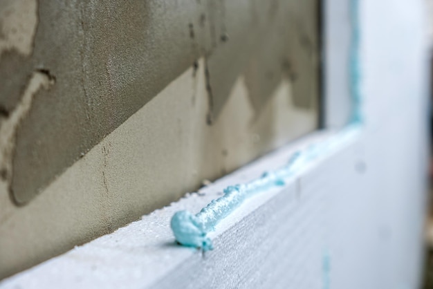 Installazione di lastre isolanti in polistirolo sulla parete della facciata della casa per la protezione termica.