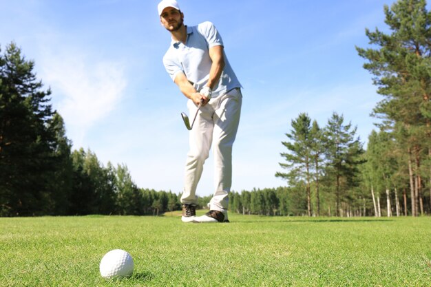 Integrale del giocatore di golf che gioca a golf il giorno soleggiato. Giocatore di golf maschio professionista che prende colpo sul campo da golf.