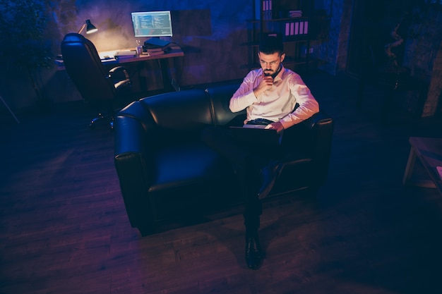 Integrale dell'uomo d'affari si siede sul lavoro dello strato di cuoio sul computer portatile