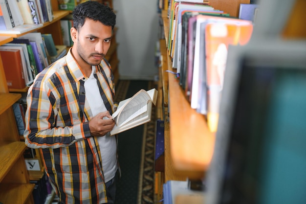 Intelligente studente maschio arabo o indiano o libero professionista in eleganti abiti casual in biblioteca