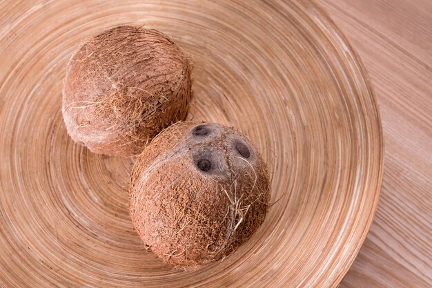 Intere noci di cocco sul piatto su fondo di legno naturale.