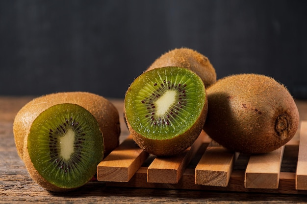 Interi kiwi maturi e mezzo kiwi su fondo di legno