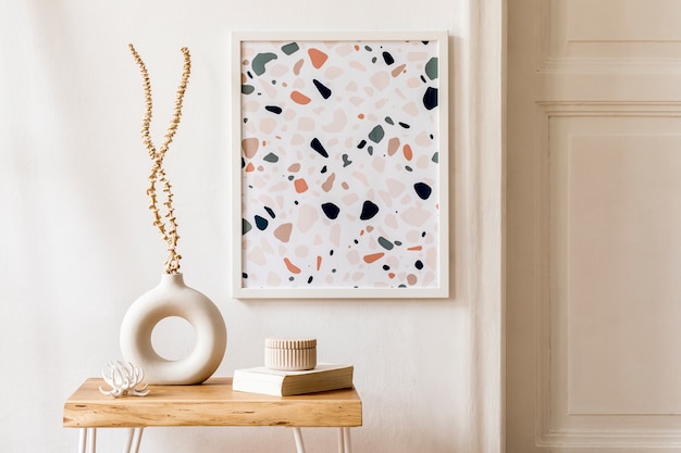 Interior design del soggiorno con eleganti fiori secchi in vaso, tavolino in legno, cornice per poster, plaid e accessori personali nell'arredamento della casa moderna