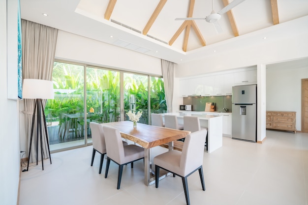 Interior design di lusso nel salotto di ville con piscina. Spazio arioso e luminoso con alto soffitto rialzato con cucina a vista