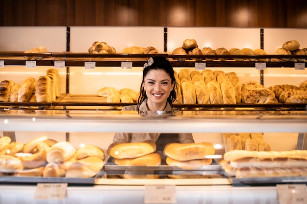 Interiore del negozio di panetteria e lavoratrice che vende pasticceria e pane freschi e gustosi