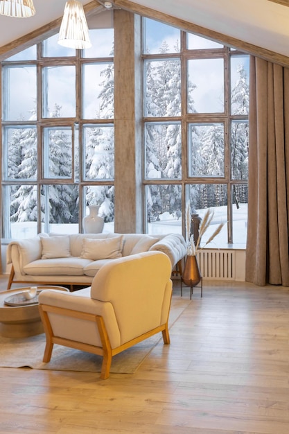 Interni accoglienti e caldi di un elegante chalet di campagna con un'enorme finestra panoramica che si affaccia sulla foresta invernale decorazioni in legno a pianta aperta colori caldi e un focolare familiare
