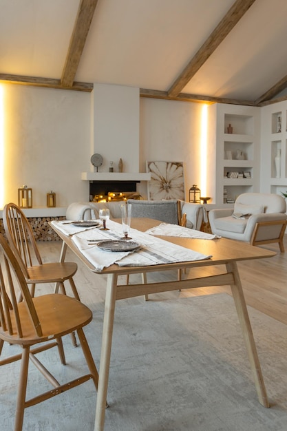 Interni accoglienti e caldi di una casa di campagna chic con finiture in legno a pianta aperta colori caldi e una vista sul focolare familiare del tavolo della zona pranzo e della tavola