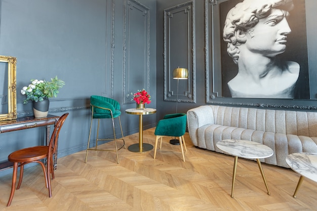 Interni chic della stanza in stile rinascimentale del XIX secolo con mobili di lusso moderni. le pareti di nobile colore scuro sono decorate con stucchi e cornici dorate, parquet in legno.