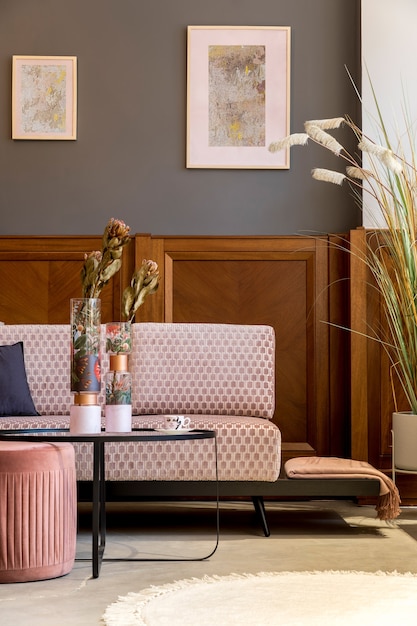 Interni eleganti del soggiorno con divano in velluto rosa design elegante pouf tavolino poster piante cuscini decorazioni e accessori personali decorazioni per la casa moderna e messa in scena domestica