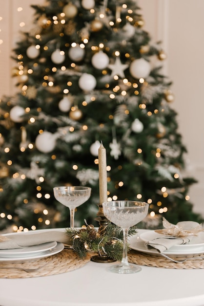 Interni eleganti e luminosi del soggiorno con un albero di Natale e un tavolo festivo