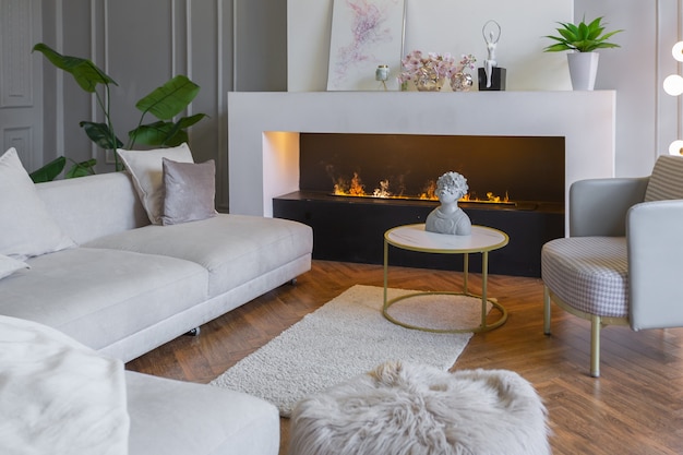 Interni minimalisti di un appartamento ultra moderno a pianta aperta con pareti bianche e grigie con un rilievo e mobili imbottiti eleganti grigi e finestre enormi