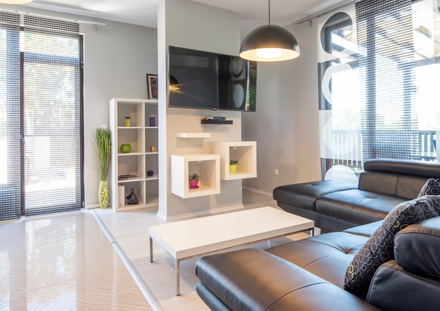 Interni moderni del soggiorno con comodo divano in pelle nera