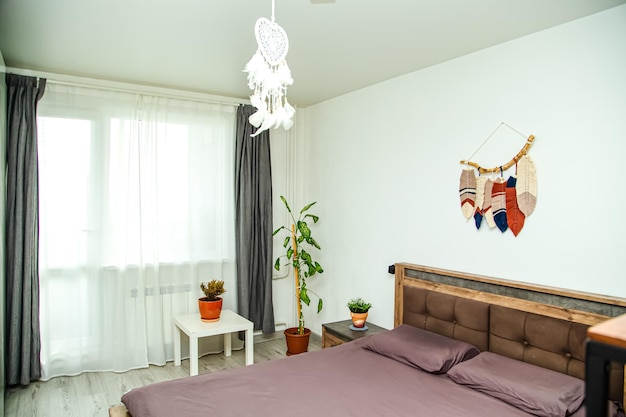 Interni moderni della camera da letto con elementi in stile boho Comodini da letto grandi e pannelli macrame sulla parete