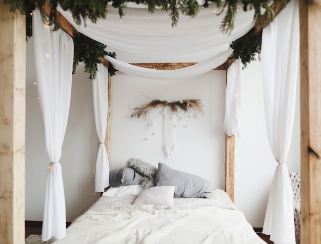 interni moderni della camera da letto in stile scandinavo con un letto accogliente con baldacchino e cuscini in legno
