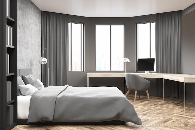 Interni moderni di camera da letto e ufficio a casa con pareti in cemento e grigio, pavimento in legno, letto principale e scrivania per computer.