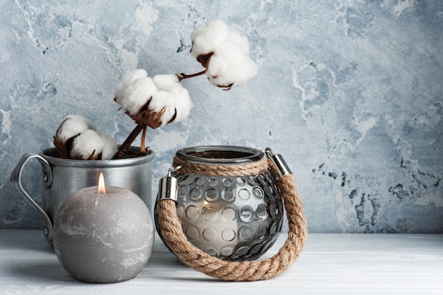 Interni scandinavi con fiori di cotone e candele accese in una disposizione minimalista.