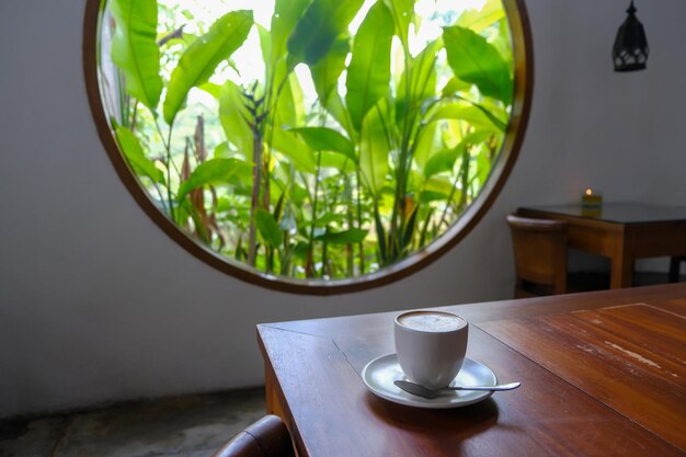 Interno accogliente del caffè con finestra rotonda che si affaccia su un verde rigoglioso