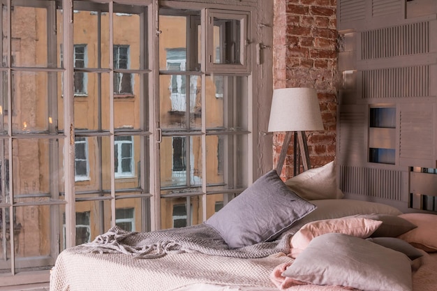 Interno appartamento loftInterno minimalista con semplice lampada da letto in legno biancheria da letto bianca Colori pastello grande finestraCamera accogliente