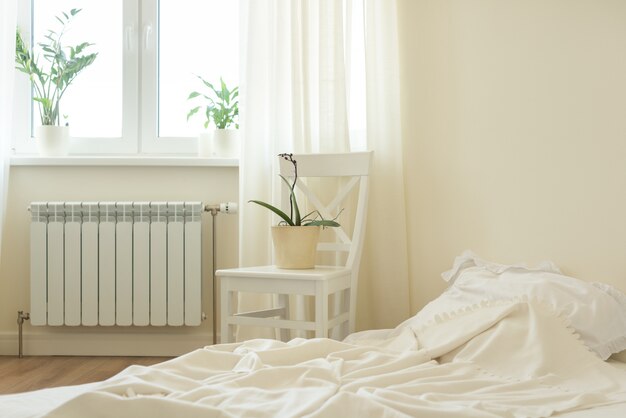 Interno camera da letto pastello chiaro, letto, sedia bianca, finestra, barriere fotoelettriche.