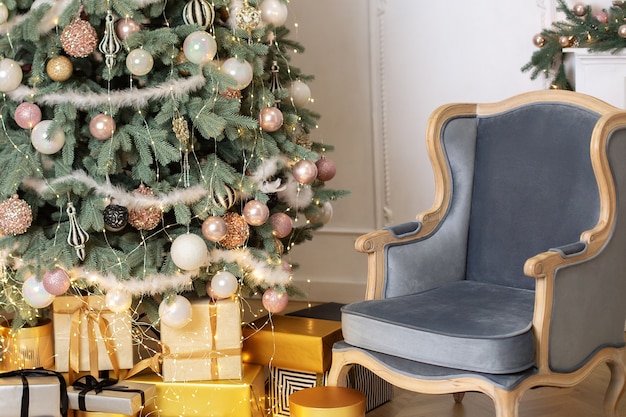 Interno classico del soggiorno con poltrona blu e regali di albero di Natale chic decorati