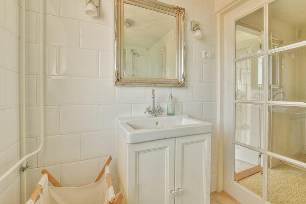 Interno del bagno con lavabo in ceramica sotto specchio e porta in vetro