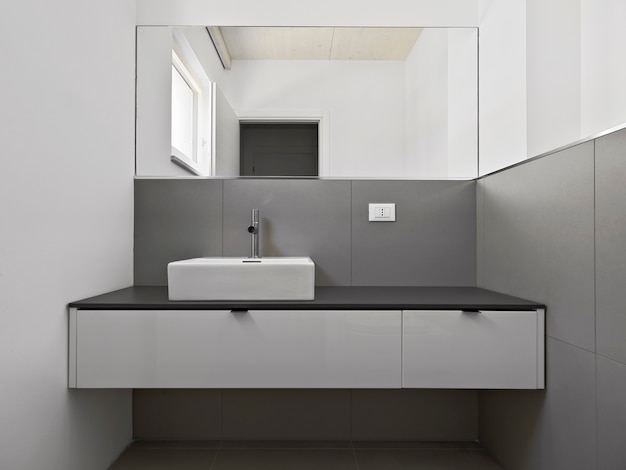 Interno del bagno moderno in primo piano il mobile lavabo e lo specchio