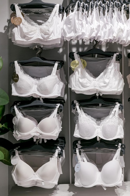 Interno del negozio di biancheria moderno e alla moda Una fila di reggiseni bianchi e beige sono appesi