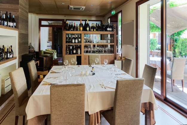 Interno del ristorante retrò con scaffali per vino e tavoli con sedie e bicchieri sullo sfondo. Decorazione del bar vintage italiano. Nessuno dentro. Arredamento del bar dell'Hotel per feste in Italia.