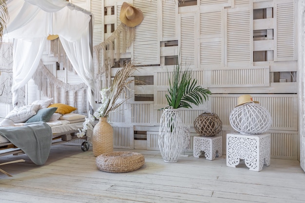 Interno della camera da letto in stile balinese. letto a baldacchino con tanti tessuti per la decorazione e articoli in vimini in tenui colori pastello