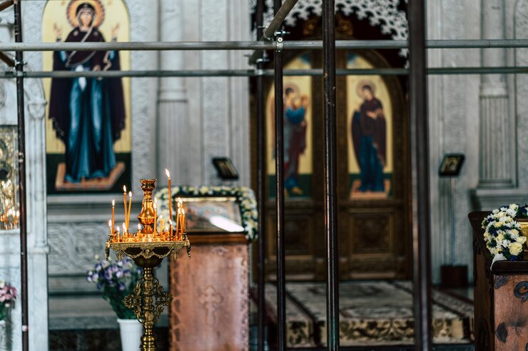 Interno della chiesa cristiana con candele accese Candele accese poste su candeliere ornamentale dorato all'interno della tradizionale chiesa cristiana con sfondo sfocato