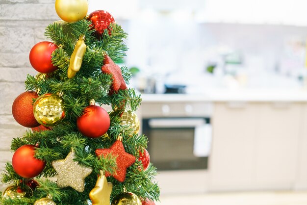 Interno della cucina grigio chiaro come sfondo sfocato e rosso con decorazioni natalizie in oro sul cuoco dell'albero...