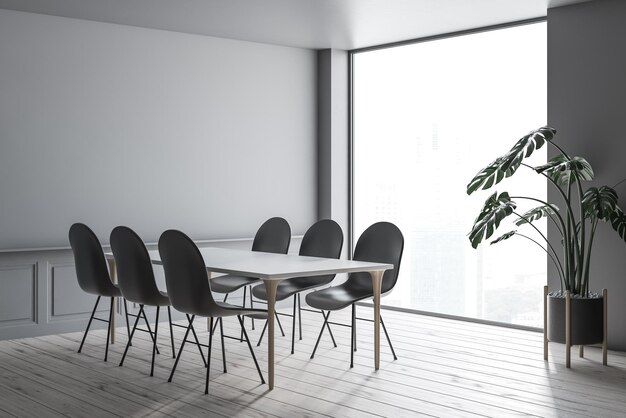 Interno della moderna sala da pranzo con pareti grigie, pavimento in legno, tavolo bianco con gambe in legno e sedie grigie in piedi intorno ad esso. rappresentazione 3d