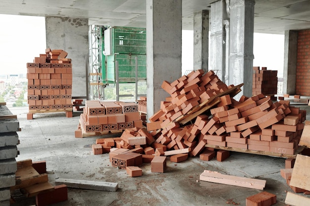 Interno di condominio incompiuto con colonne di cemento e pile di mattoni