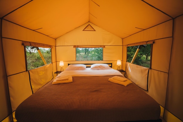 Interno di un'accogliente tenda glamping aperta con luce interna durante il tramonto Tenda da campeggio di lusso per vacanze estive all'aperto e vacanze Concetto di stile di vita