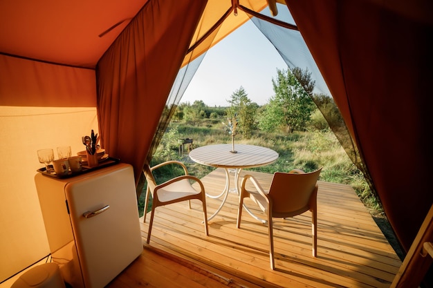 Interno di un'accogliente tenda glamping aperta con luce interna durante il tramonto Tenda da campeggio di lusso per vacanze estive all'aperto e vacanze Concetto di stile di vita